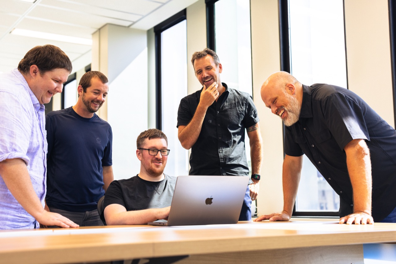 Caldera team gathered around a laptop, laughing